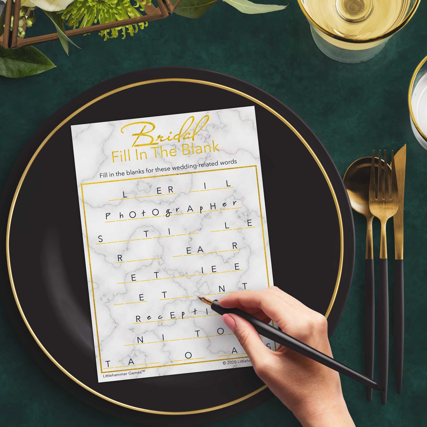 Woman with a pen playing a gold and marble Bridal Fill in the Blank game card at a dark place setting