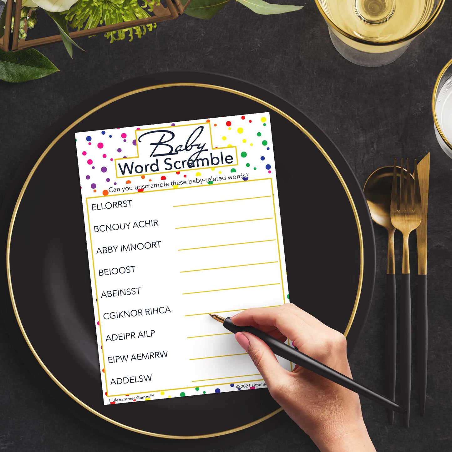 Woman playing a rainbow polka dot Baby Word Scramble game card at a green and black place setting
