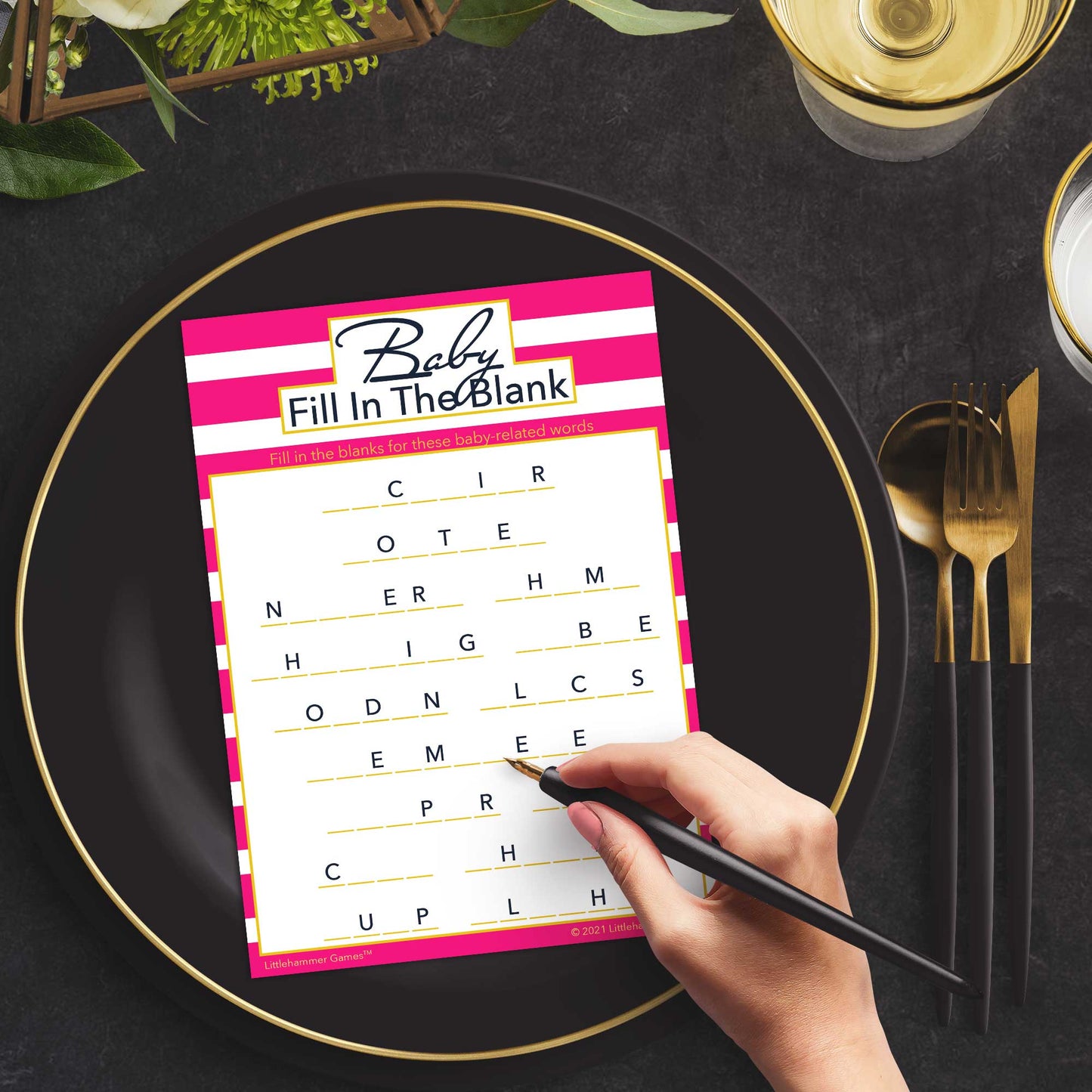 Woman with a pen playing a pink-striped Baby Fill in the Blank game card at a dark place setting