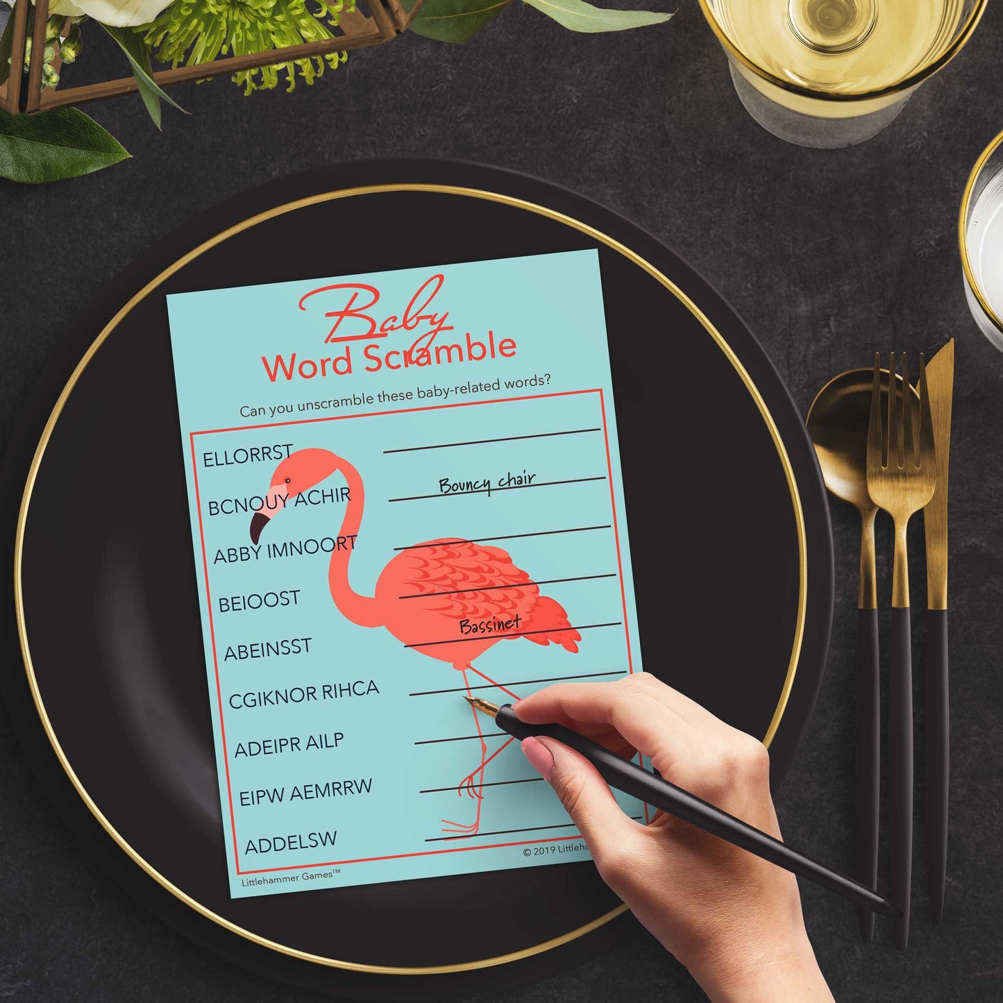 Woman playing a flamingo Baby Word Scramble game card at a black and slate place setting