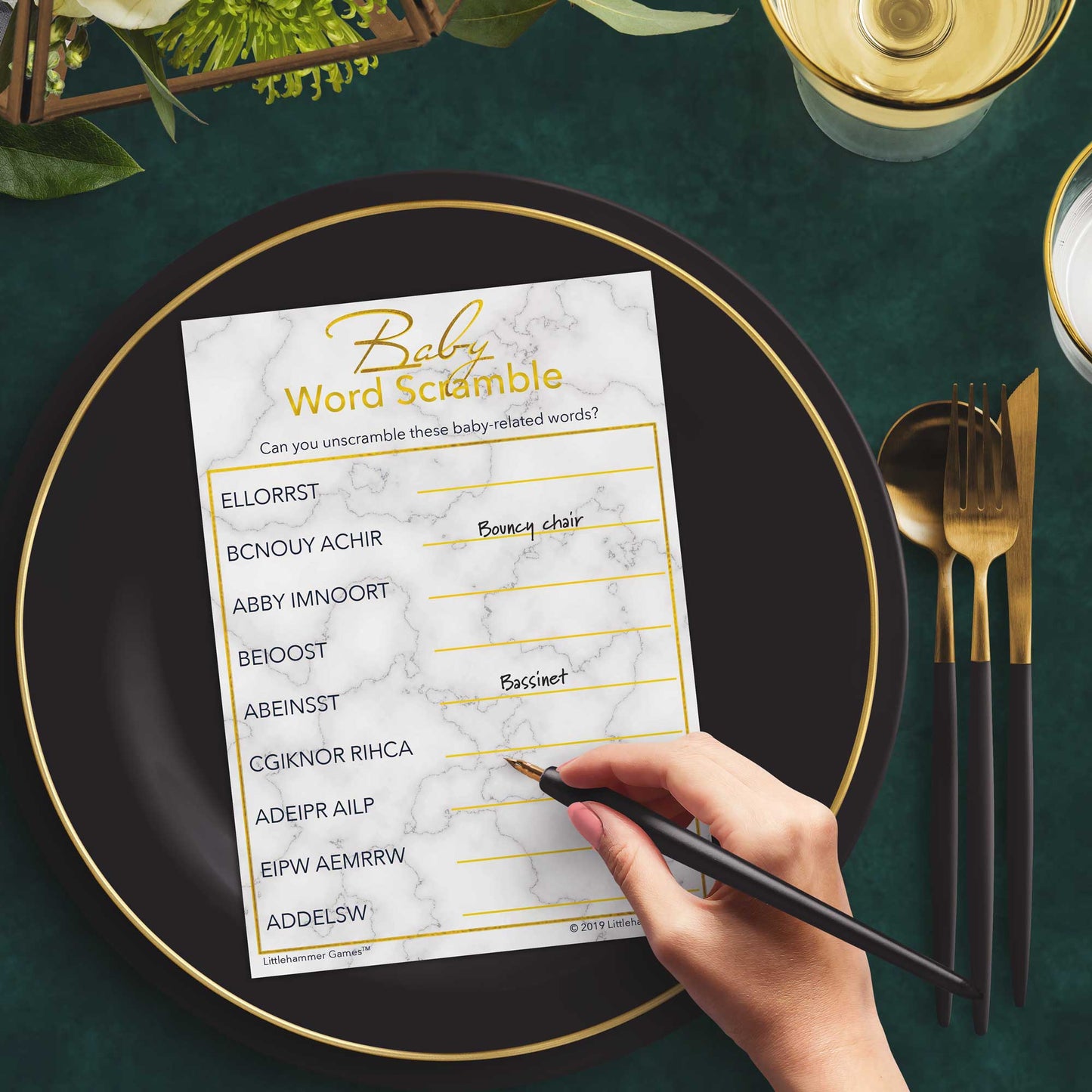 Woman playing a gold and marble Baby Word Scramble game card at a green and black place setting