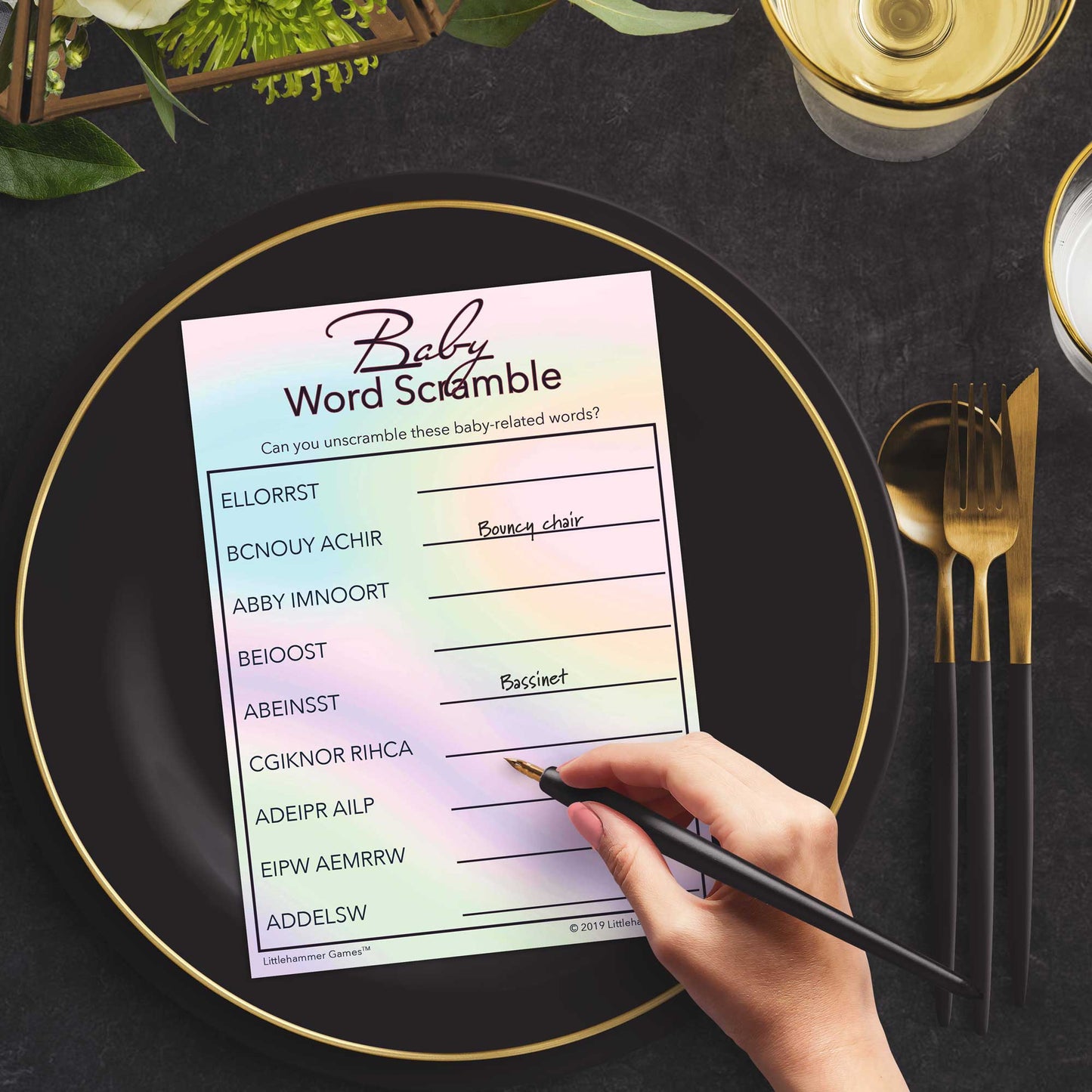 Woman playing a rainbow hologram Baby Word Scramble game card at a black and slate place setting