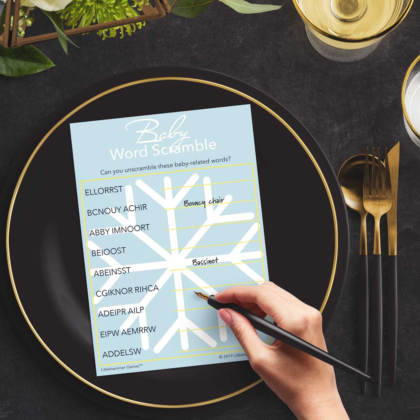 Woman playing a snowflake Baby Word Scramble game card at a black and slate place setting