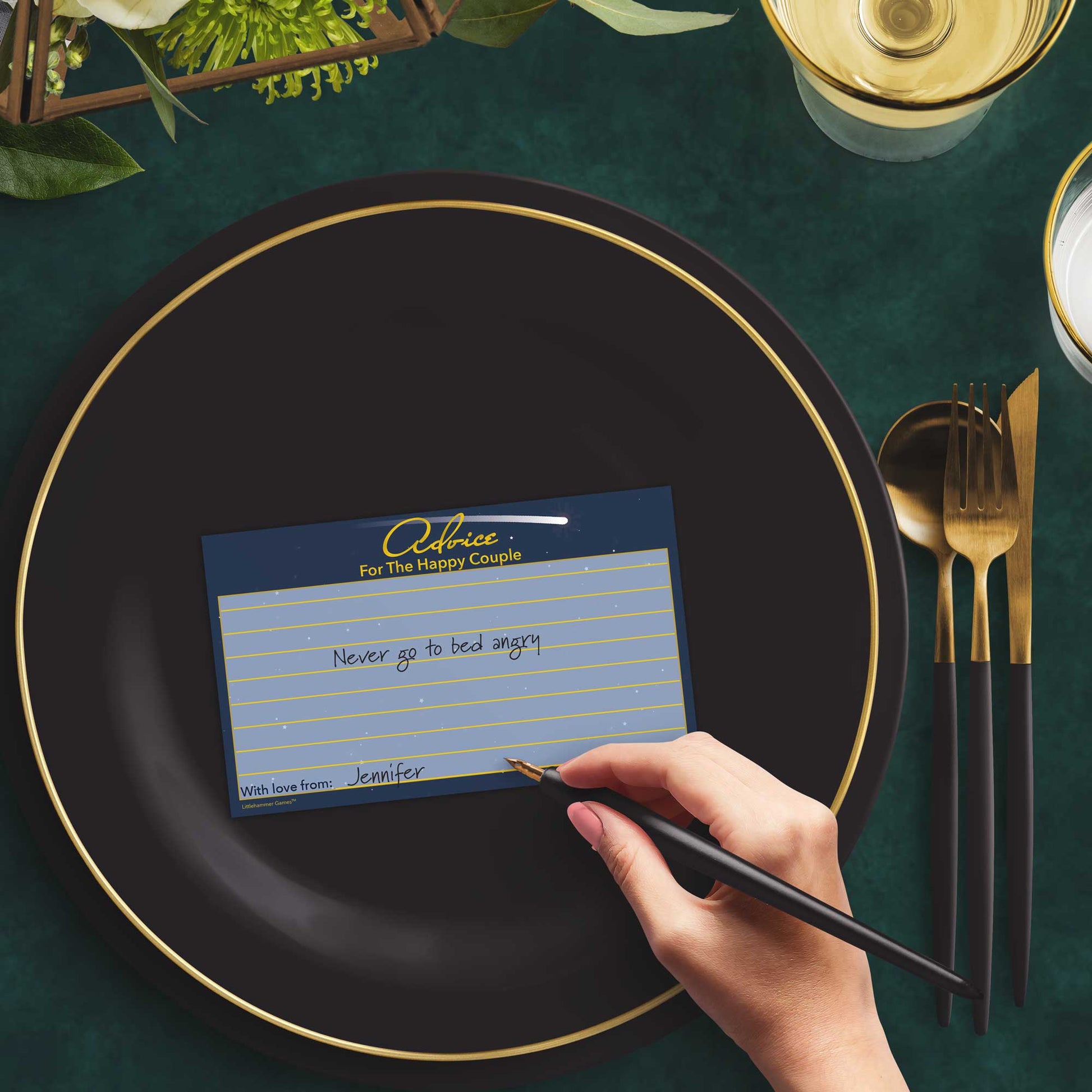 Woman with a pen sitting at a dark place setting with a black and gold plate filling out a celestial-themed Advice for the Happy Couple card