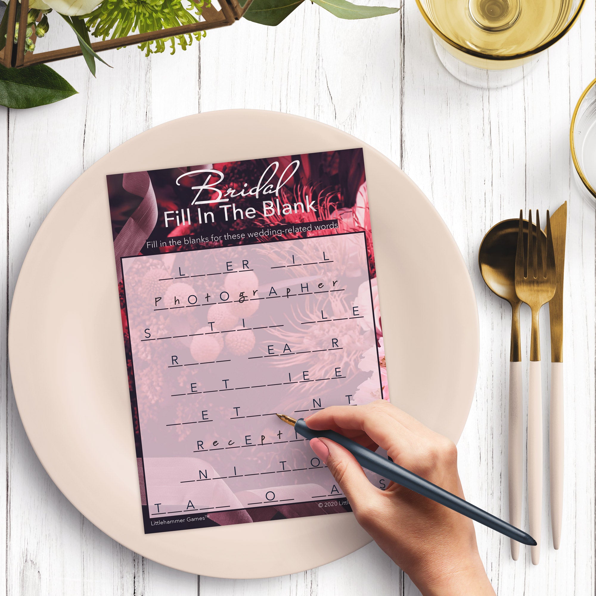 Woman with a pen playing a dark floral Bridal Fill in the Blank game card at a dark place setting