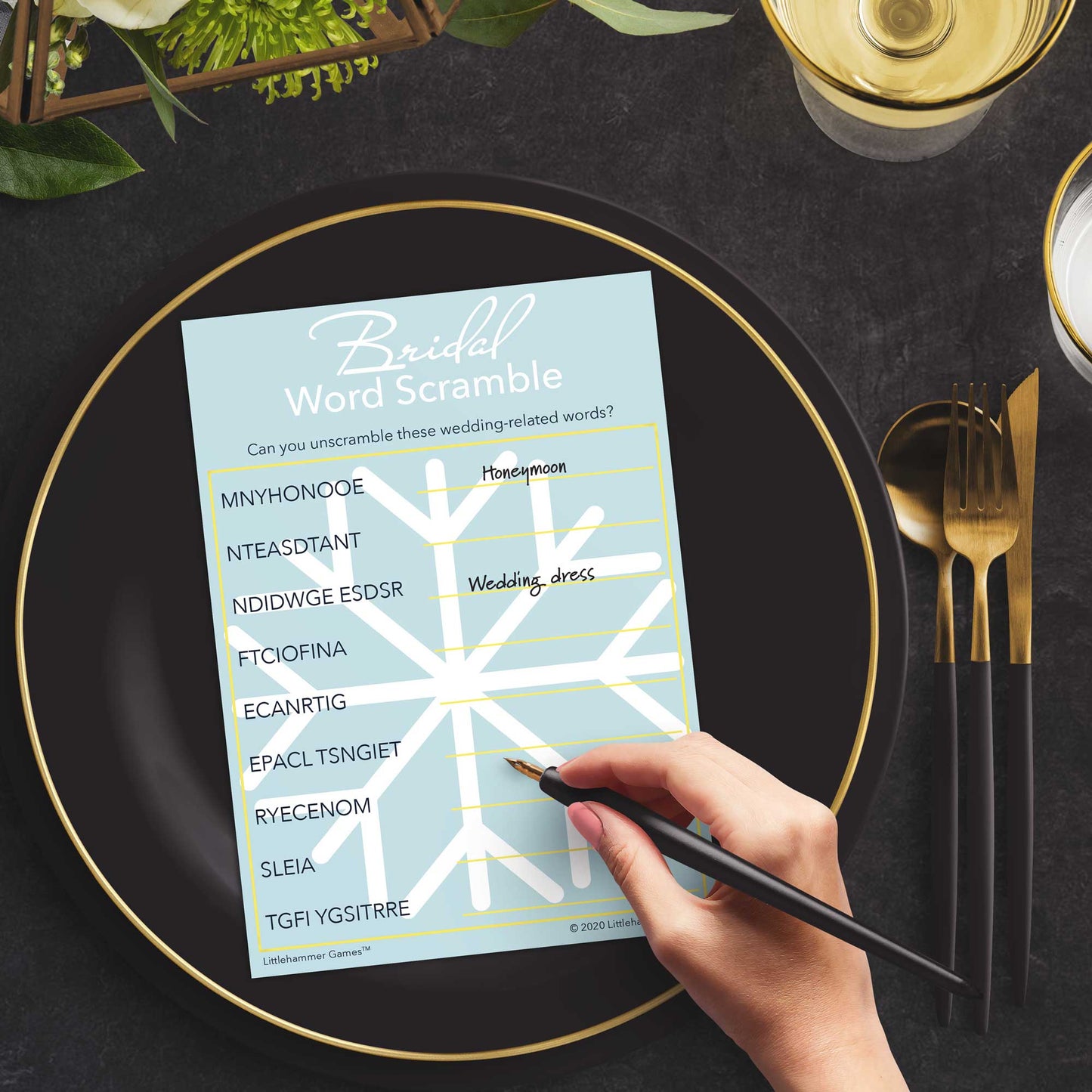 Woman with a pen playing a snowflake Bridal Word Scramble game card at a dark place setting