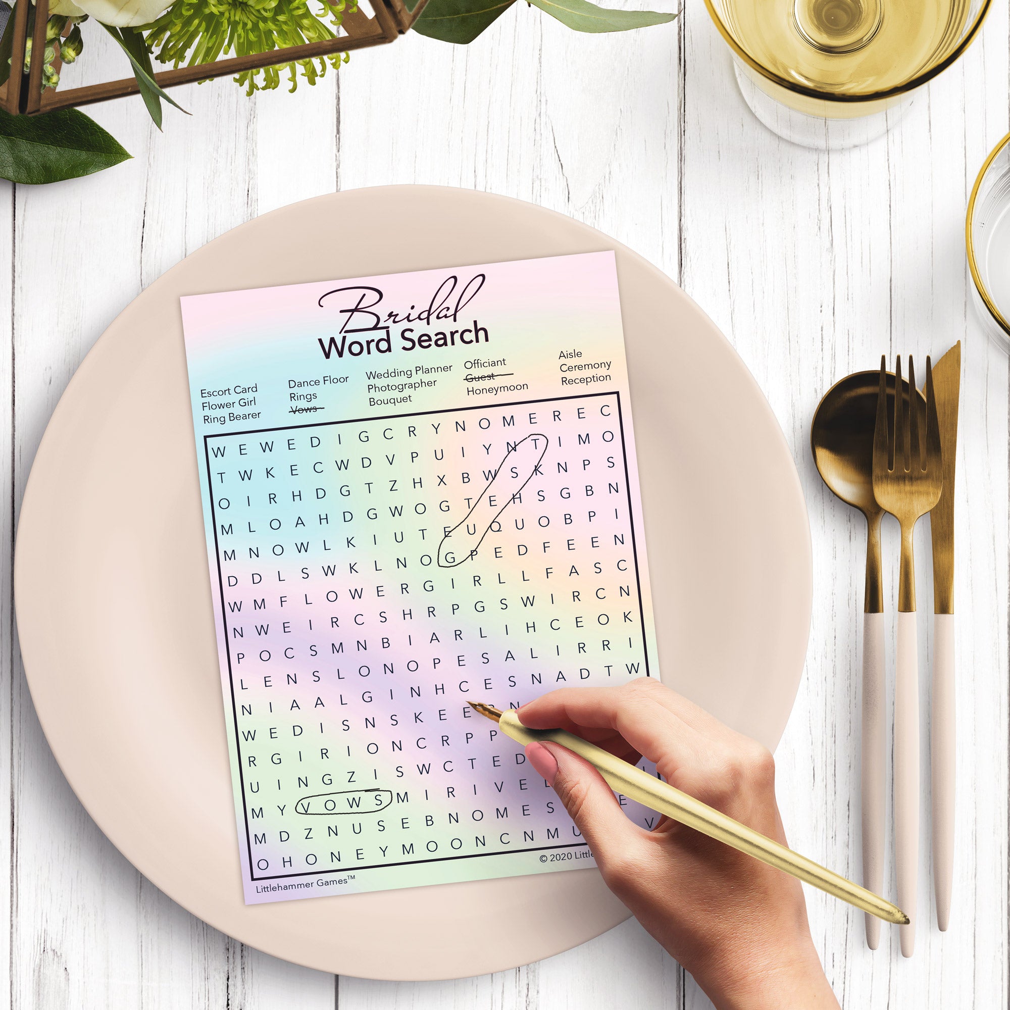Woman with a pen playing a hologram-themed Bridal Word Search game card at a dark place setting