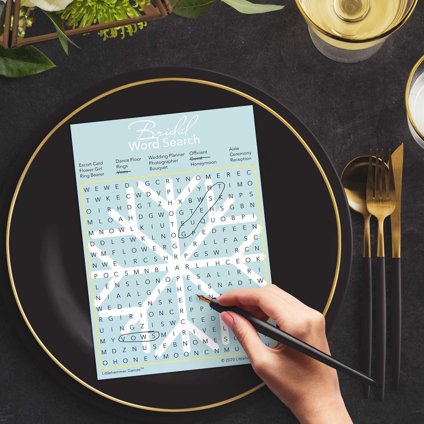 Woman with a pen playing a snowflake Bridal Word Search game card at a dark place setting