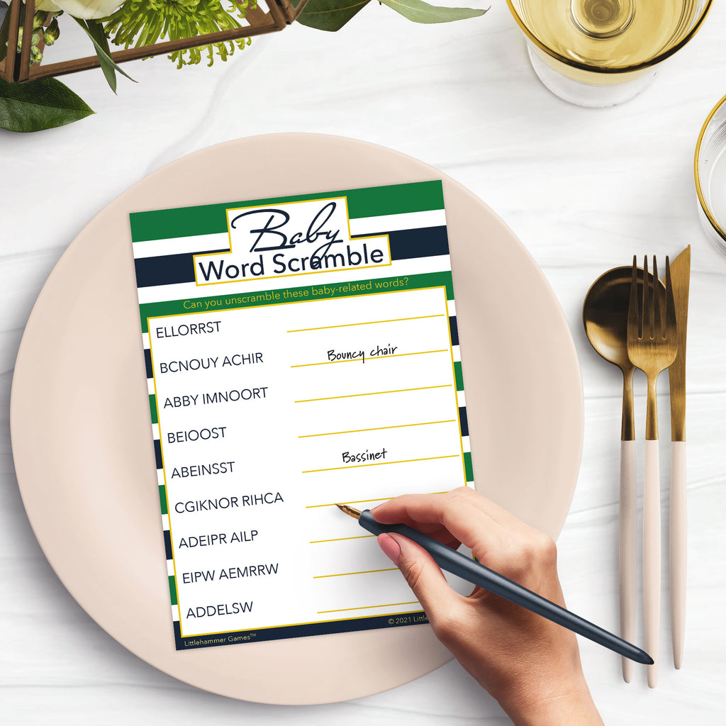 Woman’s hand holding a pen playing a green and navy-striped Baby Word Scramble game card at a light place setting