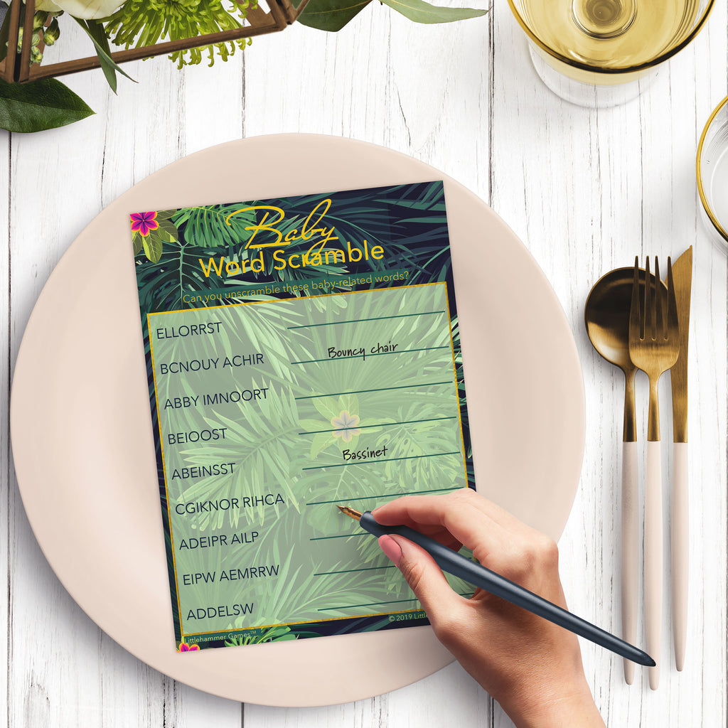 Woman’s hand holding a pen playing a tropical leaves Baby Word Scramble game card at a light place setting
