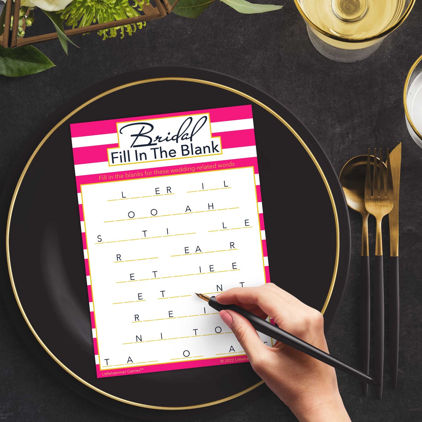 Woman with a pen playing a pink-striped Bridal Fill in the Blank game card at a dark place setting