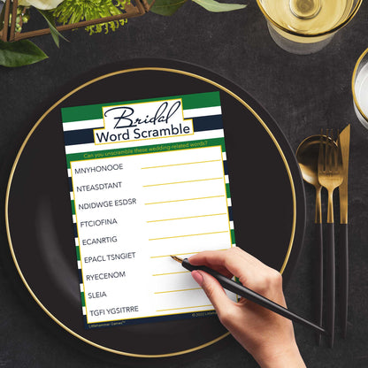 Woman with a pen playing a green and navy-striped Bridal Word Scramble game card at a dark place setting