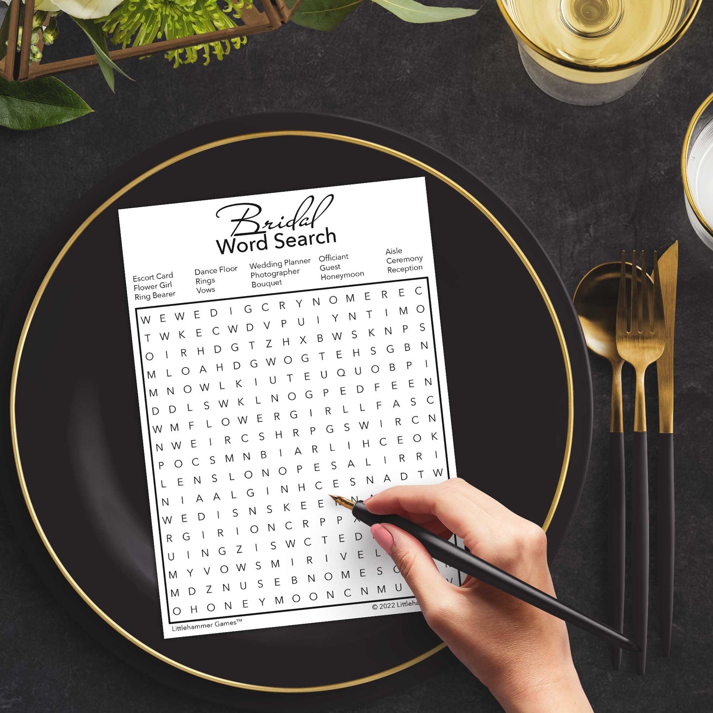 Woman with a pen playing a black and white Bridal Word Search game card at a dark place setting