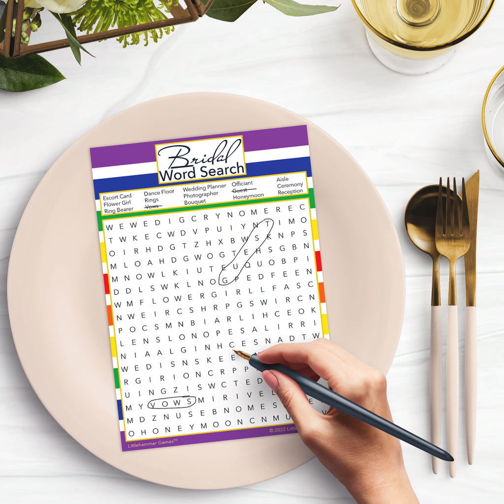 Woman with a pen playing a rainbow-striped Bridal Word Search game card at a dark place setting