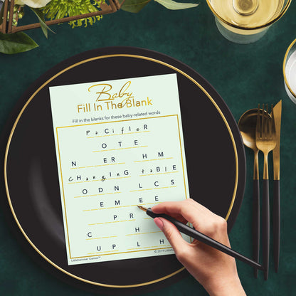Woman with a pen playing a mint and gold Baby Fill in the Blank game card at a dark place setting