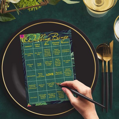 Woman with a pen sitting at a table with a tropical themed Wedding Bingo game card on a black and gold plate at a dark place setting
